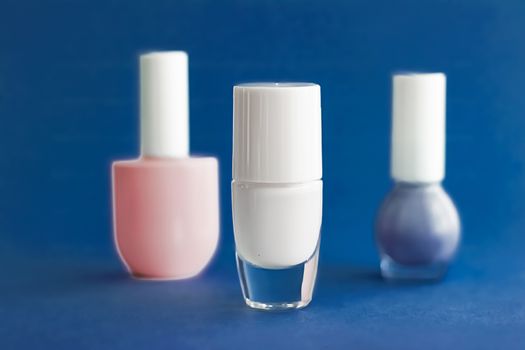 Nail polish bottles on dark blue background, beauty branding