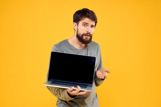 man with laptop wireless technology internet lifestyle work yellow isolated background. High quality photo