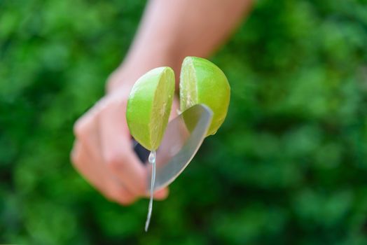 The man use knife split the fresh green lemon in midair