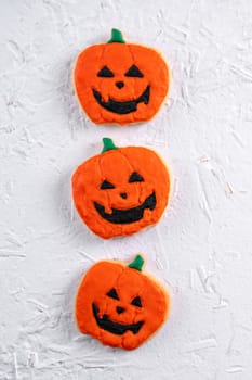 Top view of Halloween festive decorated icing gingerbread sugar cookies on white background with copy space and flat lay layout.