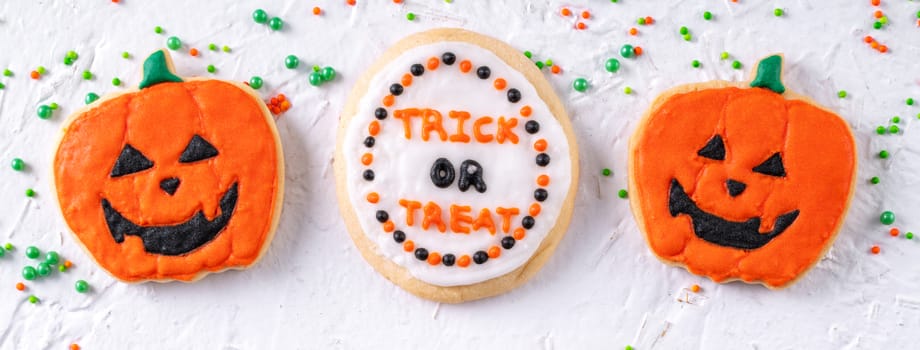 Top view of Halloween festive decorated icing gingerbread sugar cookies on white background with copy space and flat lay layout.