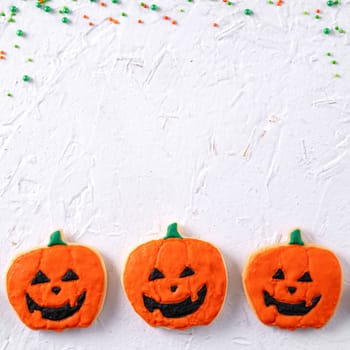 Top view of Halloween festive decorated icing gingerbread sugar cookies on white background with copy space and flat lay layout.