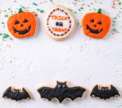 Top view of Halloween festive decorated icing gingerbread sugar cookies on white background with copy space and flat lay layout.