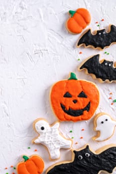 Top view of Halloween festive decorated icing gingerbread sugar cookies on white background with copy space and flat lay layout.