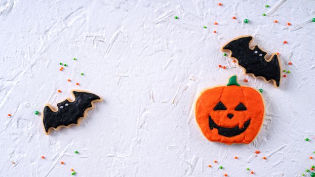 Top view of Halloween festive decorated icing gingerbread sugar cookies on white background with copy space and flat lay layout.