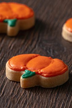 Close up of decorating cute Halloween pumpkin gingerbread cookies with frosting icing cream topping bag.