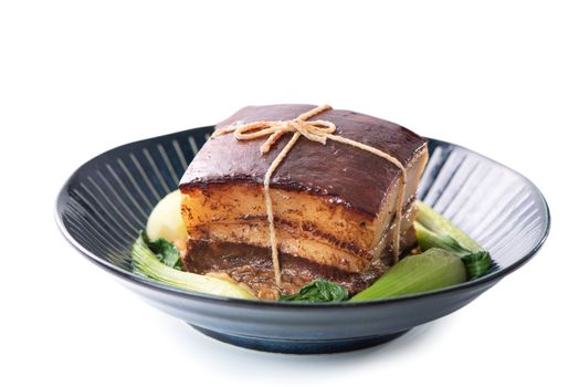 Isolated Dong Po Rou (Dongpo pork meat) in a beautiful plate with green vegetable, traditional festive food for Chinese new year cuisine meal, close up.