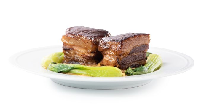 Isolated Dong Po Rou (Dongpo pork meat) in a beautiful plate with green vegetable, traditional festive food for Chinese new year cuisine meal, close up.