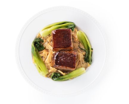 Isolated Dong Po Rou (Dongpo pork meat) in a beautiful plate with green vegetable, traditional festive food for Chinese new year cuisine meal, close up.