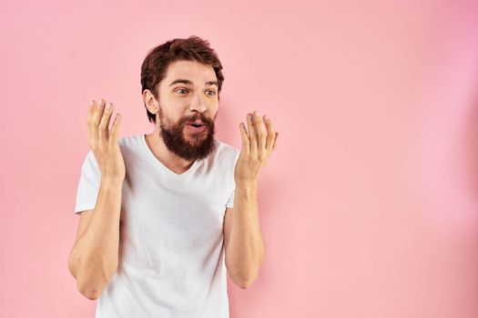 Man in white t-shirt gestures with hands emotions lifestyle cropped view pink background. High quality photo