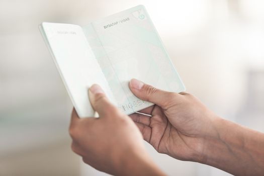 Close-Up Of Cropped Hand Holding Passport Against Clean Blurred Background