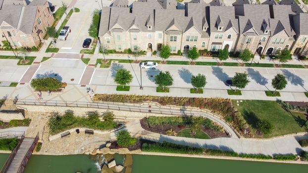 Top view new two-story townhouse near downtown Flower Mound, Texas, US. Aerial riverside and urban townhouses with compact front-yard and well trimmed landscape