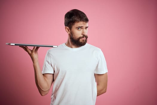 emotional man with closed laptop in hands on pink background cropped view Copy Space. High quality photo