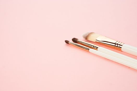 Makeup brushes on a pink background in different sizes cropped view. High quality photo