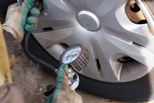 car mechanic checks the pressure in the car wheel, close up