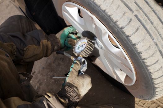 car mechanic checks the pressure in the car wheel, close up