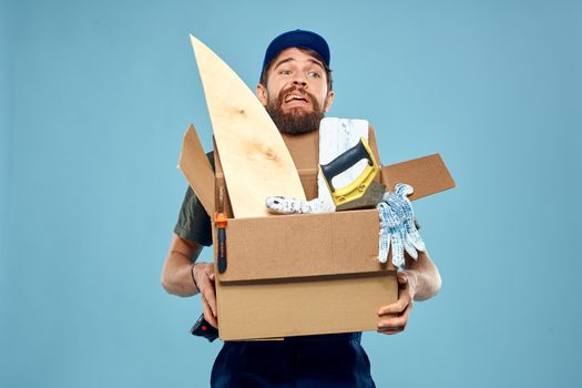 Worker man in uniform box tools construction blue background. High quality photo