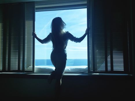 Woman looking outside the big window with sea view, luxury travel and summer vacation concept