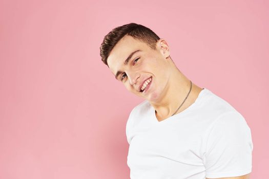 Cheerful handsome man in white t-shirt emotions pink isolated background. High quality photo