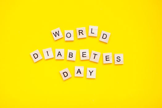 The inscription from wooden blocks world diabetic day on a yellow background. Diabetes.