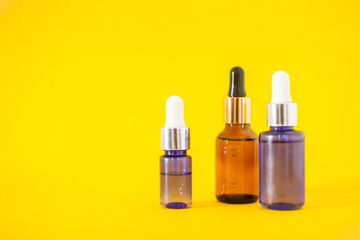 Cosmetic bottles with serum on a bright yellow background. Cosmetology and beauty concept.