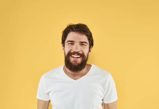 Close-up portrait of a happy man in a white t-shirt on a yellow background. High quality photo