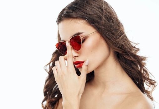 Attractive lady with sunglasses on her face on a light background. High quality photo