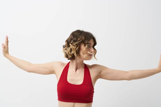 the girl is engaged in yoga on a light background Red T-shirt gesticulating with his hands. High quality photo