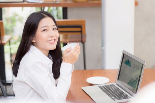 Beautiful asian young woman working online on laptop sitting at coffee shop, professional female freelancer using notebook computer with connect to internet for distance job.