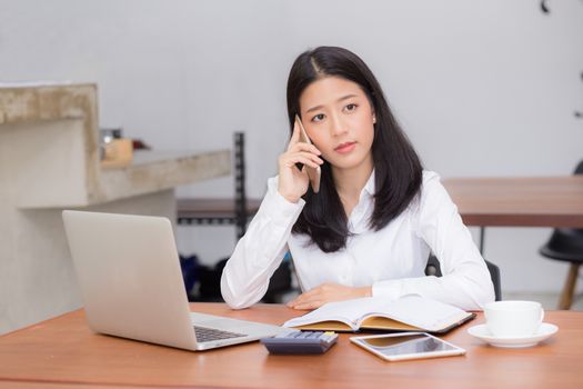 Beautiful asian young businesswoman excited and glad of success with laptop, girl taking mobile phone and working coffee shop on cement background, career freelance business concept.