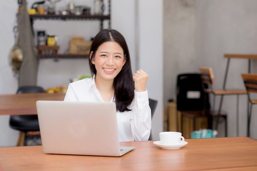 Beautiful asian young businesswoman excited and glad of success with laptop, girl using working computer coffee shop on desk, career freelance business concept.
