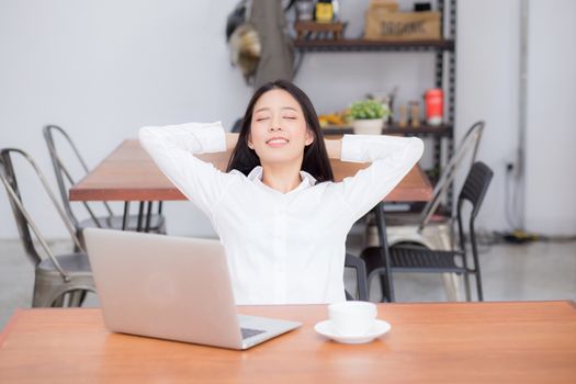 Beautiful young asian woman with laptop stretch and exercise relax after work success, modern office with copy space, freelance business concept.