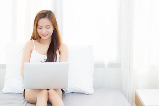Beautiful young asian woman using laptop for leisure on bedroom, girl working online with notebook freelance, business concept.