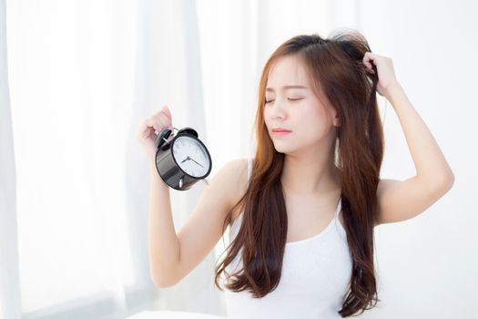 Beautiful asian young woman wake up in morning annoyed alarm clock holding hand, girl hurry wake late with appointment, lifestyle concept.