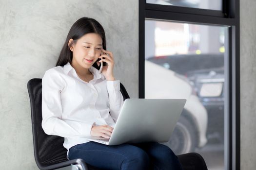 Beautiful asian young businesswoman excited and glad of success with laptop, girl taking mobile phone and working coffee shop on cement background, career freelance business concept.