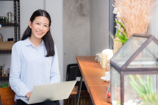 Beautiful asian young woman working online on laptop sitting at coffee shop, professional female freelancer using notebook computer with connect to internet for distance job.