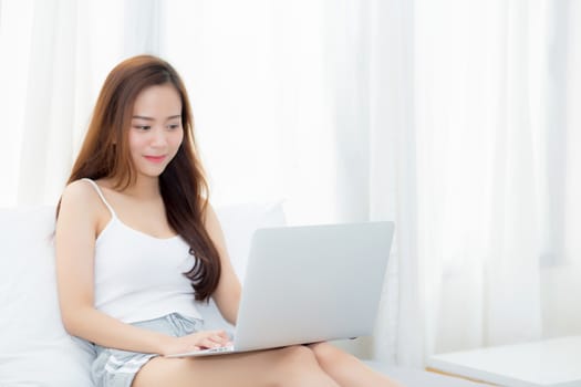 Beautiful young asian woman using laptop for leisure on bedroom, girl working online with notebook freelance, business concept.