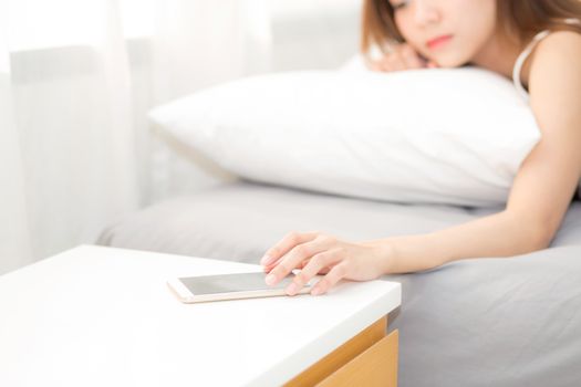 hand of woman turn off alarm on call mobile phone while wake up after sleep relax in good morning at bedroom.