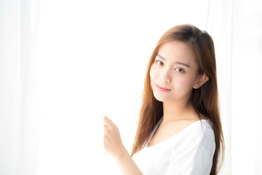 Beautiful young asian woman standing the window and smile while wake up with sunrise at morning, lifestyle and relax concept.