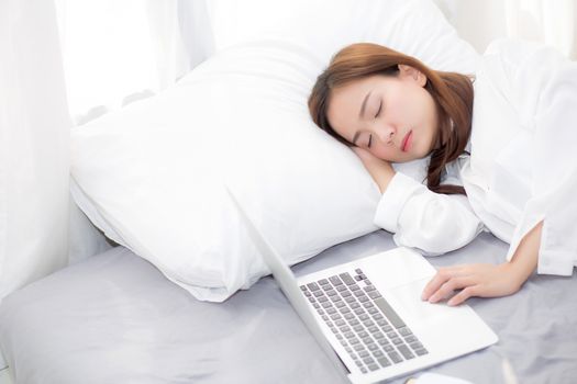 Beautiful young asian woman with laptop lying down in bedroom, girl tired sleep with computer notebook, resting and healthcare concept. 