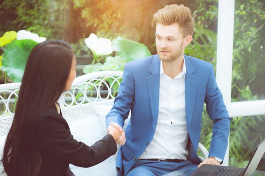 Two people happiness success business partner shaking hands in the office, businessman and businesswoman handshake successful with agreement, partnership concept.