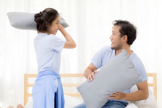 Asian young couple happy fun with playing pillow fight at bedroom, relationship of love concept.