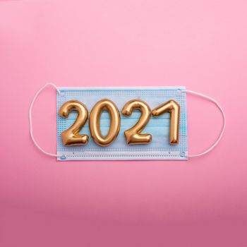Gold numbers 2021 with face mask on blue background. Happy new pandemic year