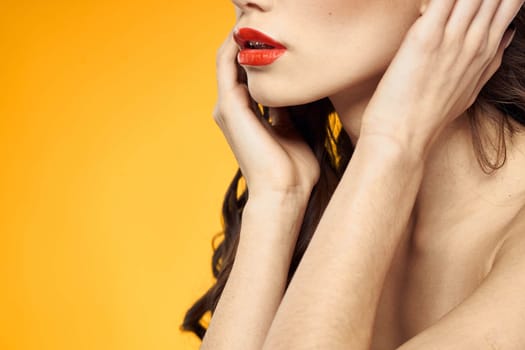 beautiful brunette red lips bare shoulders skin care yellow background. High quality photo