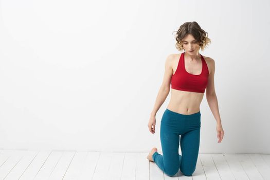 A woman in blue jeans practices yoga on a light background indoors and a slim figure in gymnastics. High quality photo