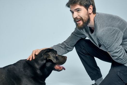 The man trains the dog indoors and gestures with his hands to execute the model's commands. High quality photo