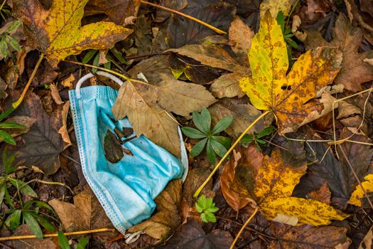 Discarded Corona mask Garbage in the dirt in colorful autumn leaves in Germany Garbage problem