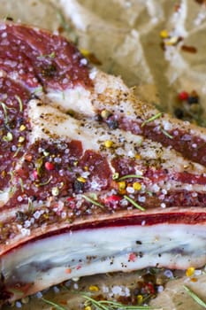 Raw beef meat on the table, spices and Rosemary, Rib eye steak ingredients. Pepper and coarse salt