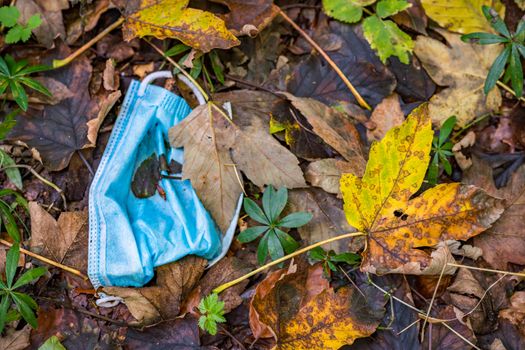 Discarded Corona mask Garbage in the dirt in colorful autumn leaves in Germany Garbage problem