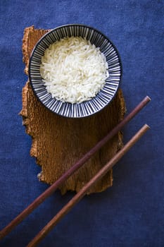 Asian tableware, raw rice, bowl and chopsticks, wooden material, ceramic bowl. Seeds of rice.